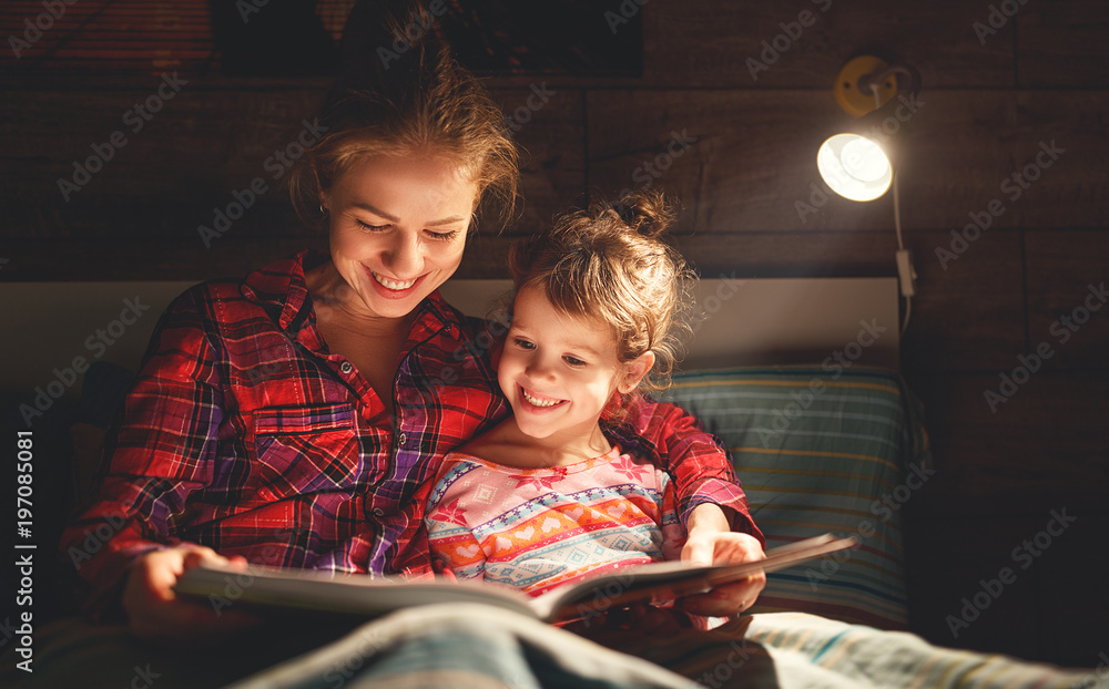 母亲和孩子睡觉前在床上看书。