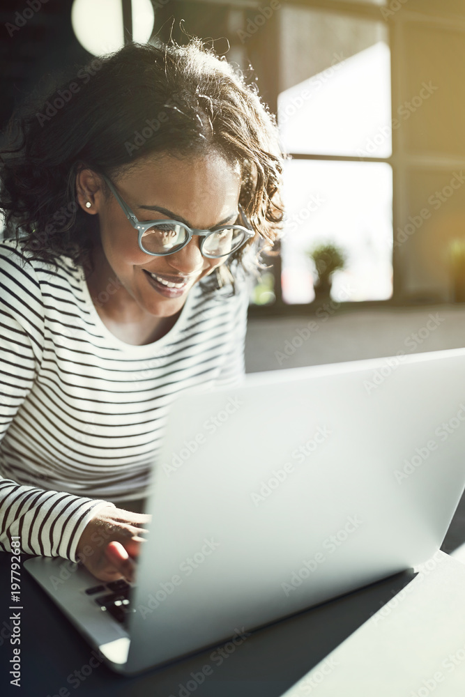 微笑的年轻非洲妇女在笔记本电脑上工作