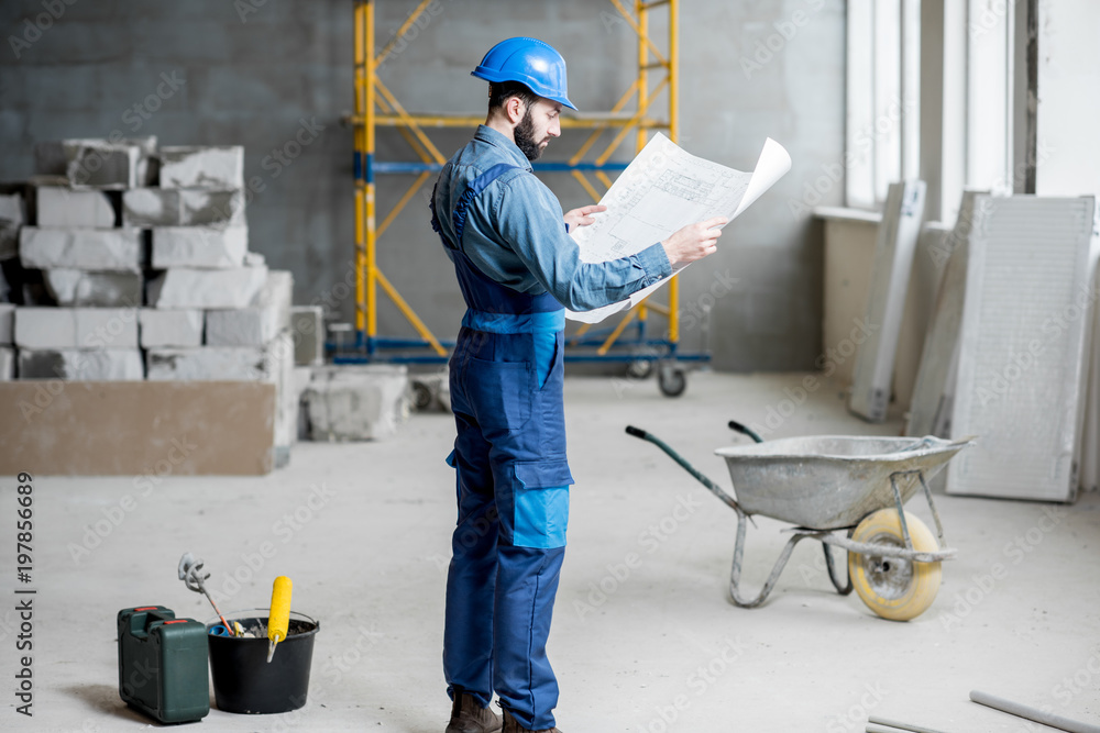 穿着工作服的建筑工人或工头熟练掌握施工现场的结构和蓝图