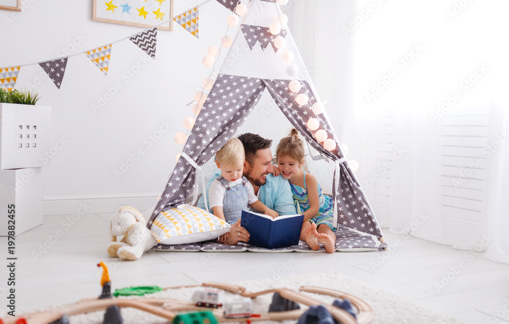家庭父亲在家里的帐篷里给孩子读书