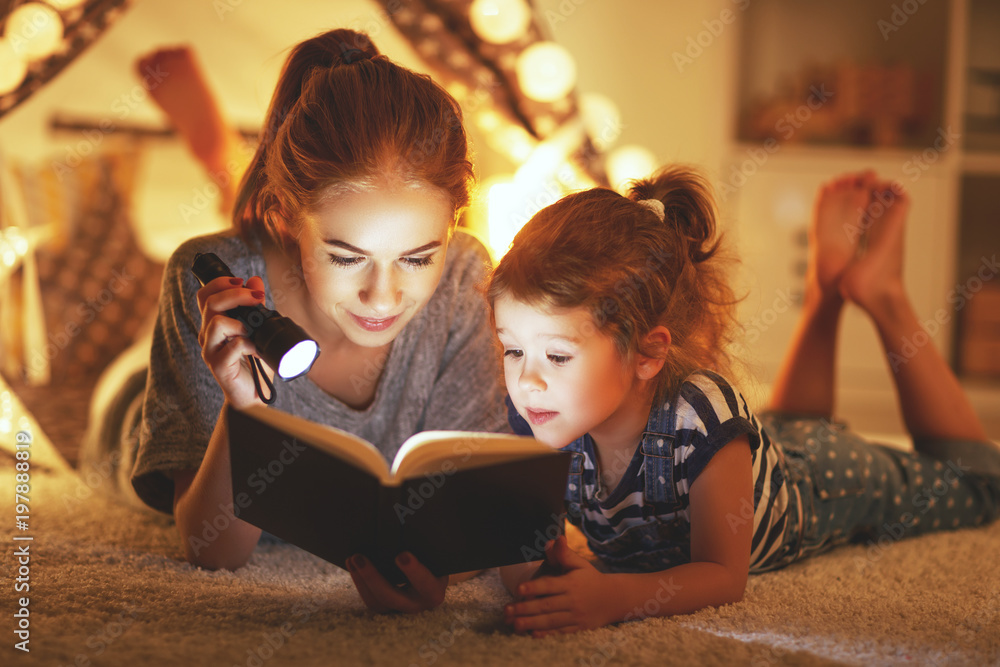 母亲和孩子女儿睡前看书和手电筒