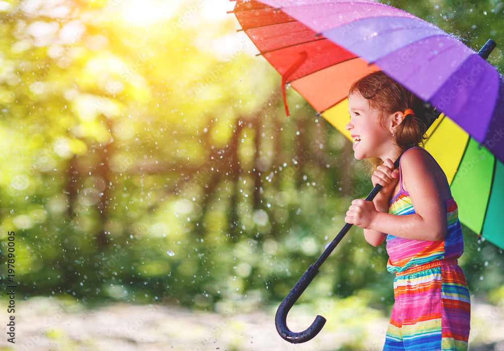 快乐的小女孩在夏天的雨水下撑着伞笑着玩耍。