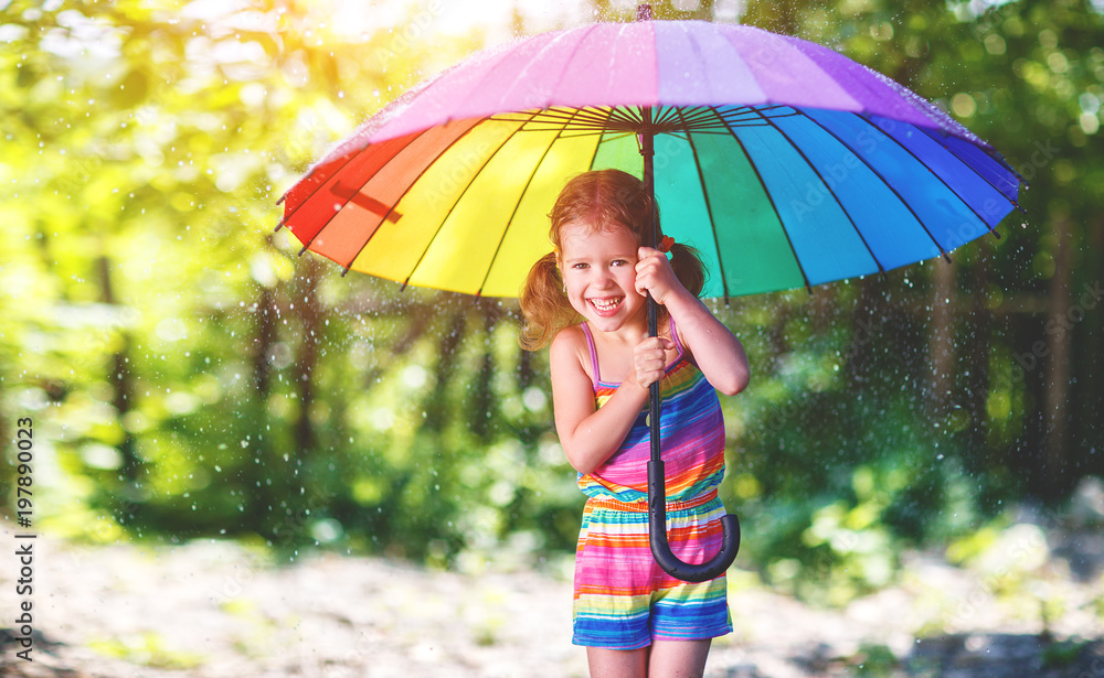 快乐的小女孩撑着伞在夏雨下嬉笑玩耍。