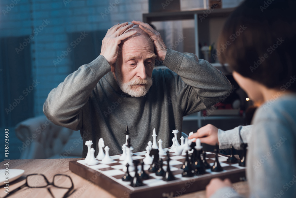 爷爷和孙子晚上在家一起下棋。