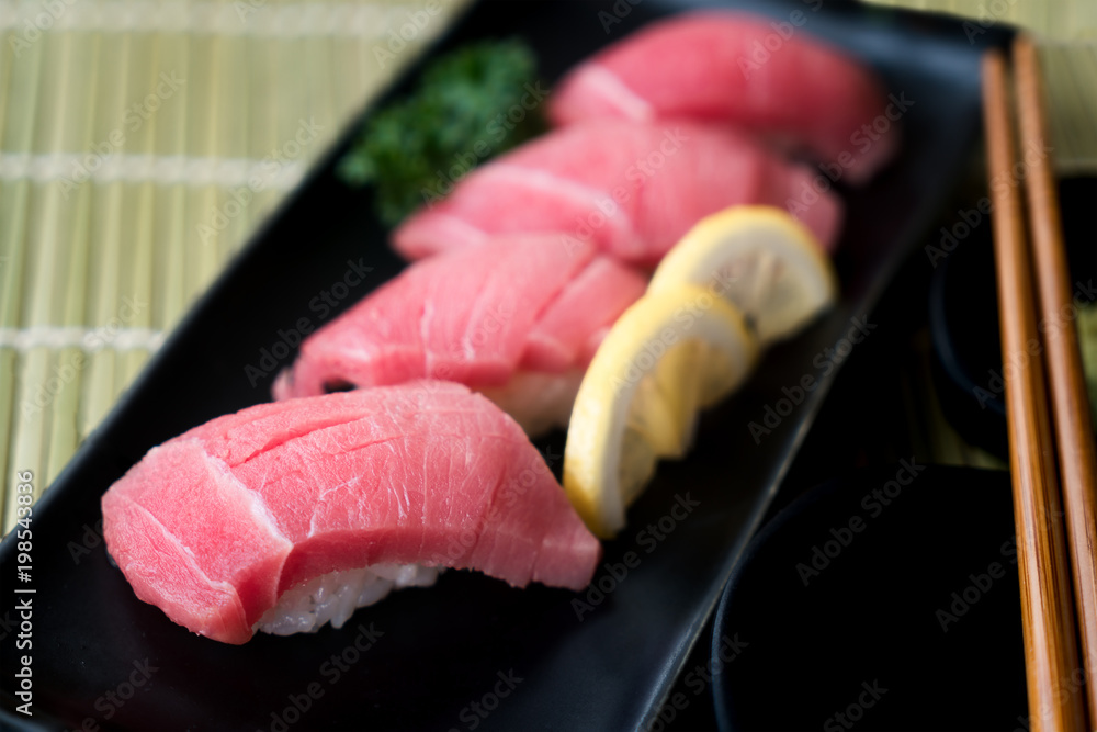 黑盘子里的Otoro金枪鱼寿司，配日本酱汁和绿叶装饰，日本食物，