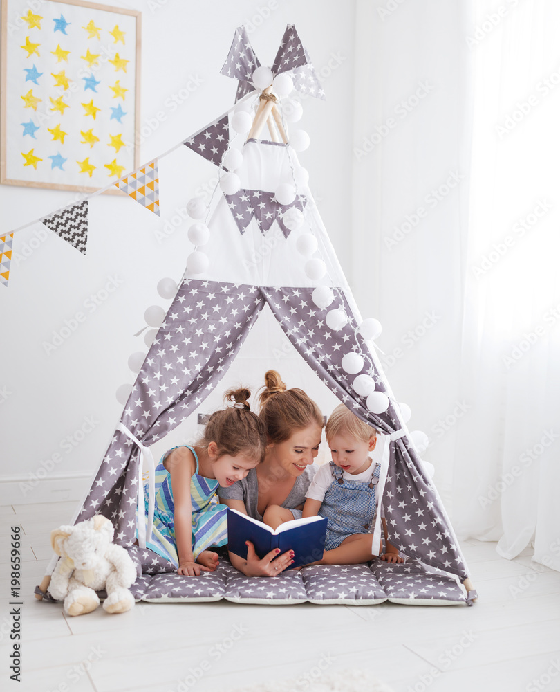 家庭母亲在家里的帐篷里给孩子们读书