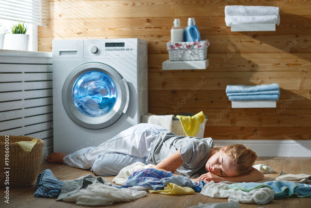 压力下疲惫的家庭主妇睡在带洗衣机的洗衣房里