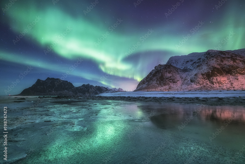 群山和海洋下的北极光。挪威美丽的自然景观