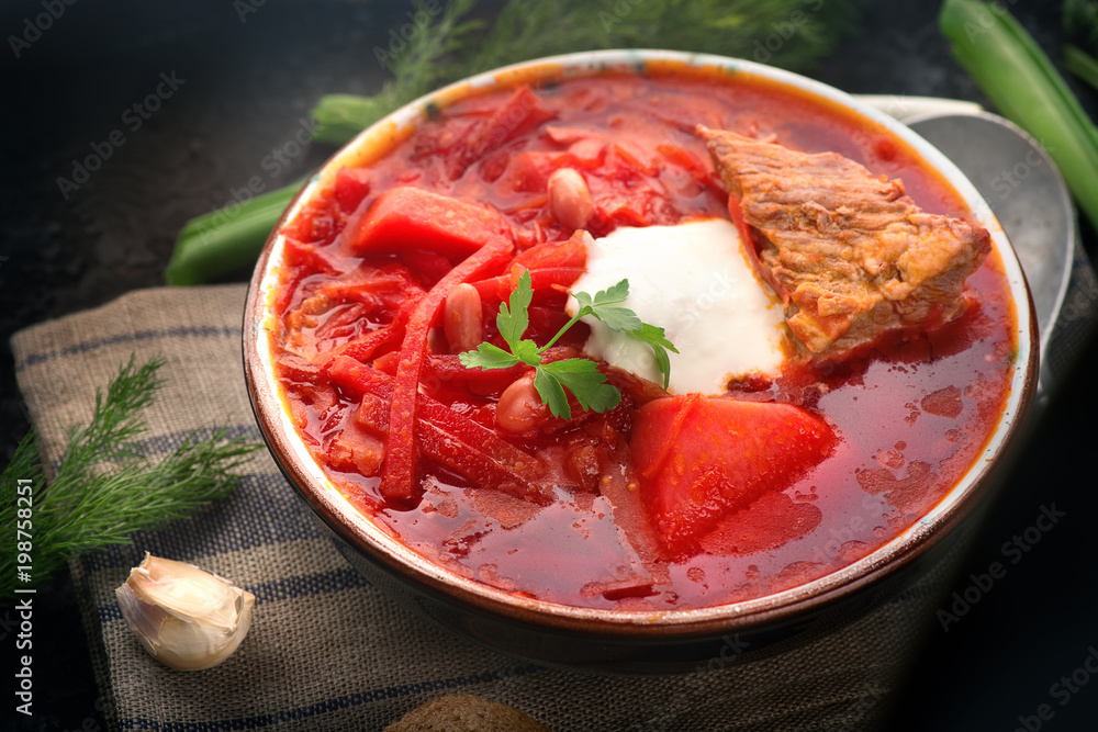 传统的乌克兰-俄罗斯罗宋汤。黑色乡村餐桌上的一盘红甜菜根汤。蜜蜂
