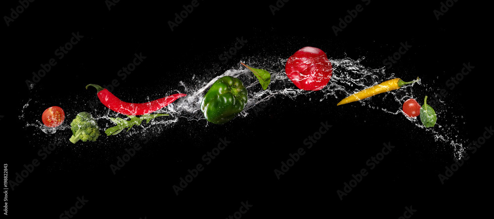 蔬菜在水中的混合物在黑色背景上飞溅。