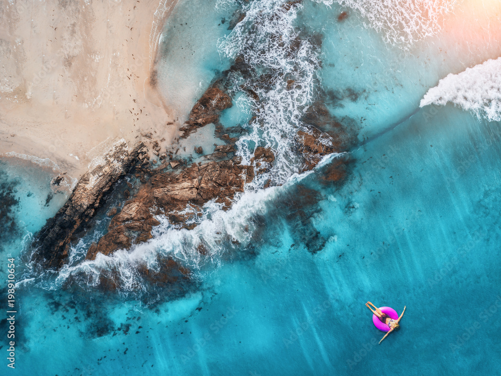 奥卢登透明绿松石海中一名年轻女子在粉色游泳圈上游泳的鸟瞰图