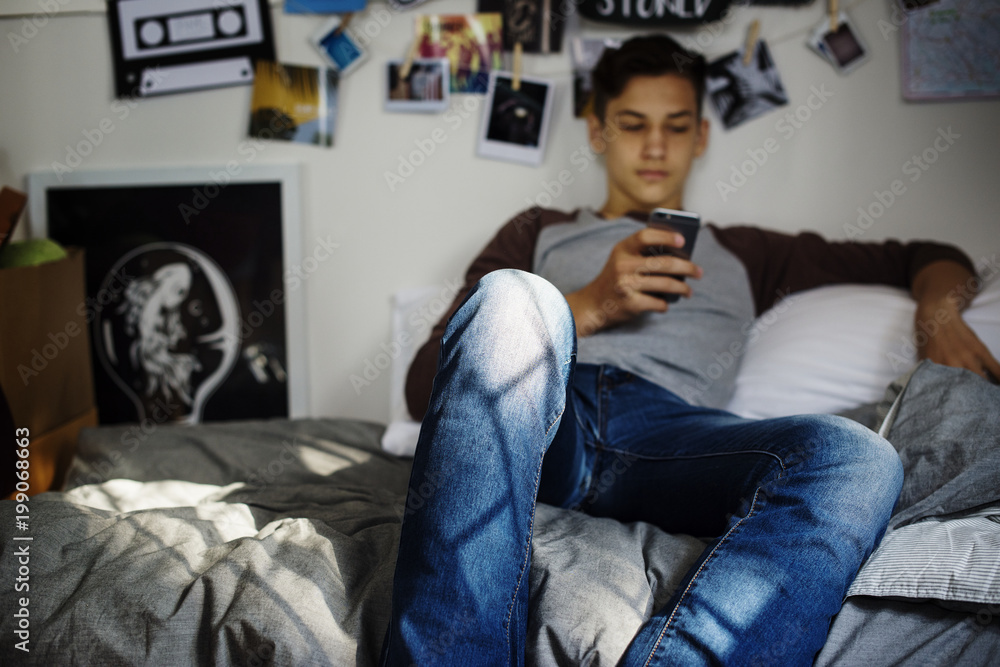 青少年男孩在卧室使用智能手机社交媒体概念