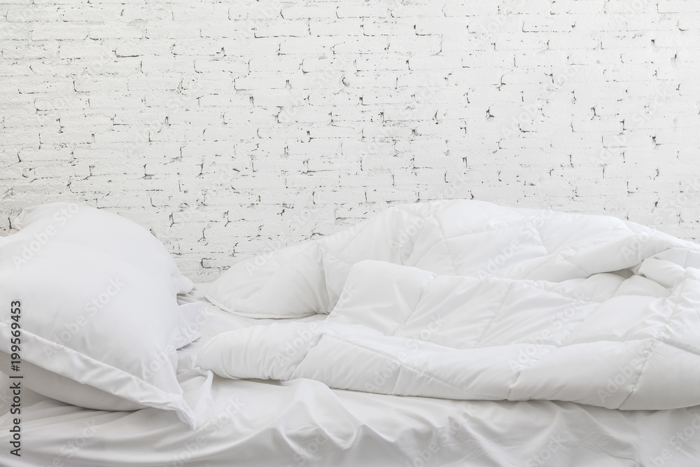 白色房间背景中的白色床单和枕头。早晨的床概念很混乱。