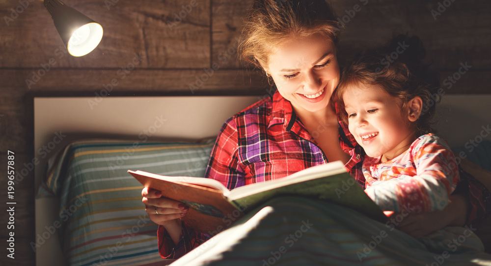 母亲和孩子睡觉前在床上看书。