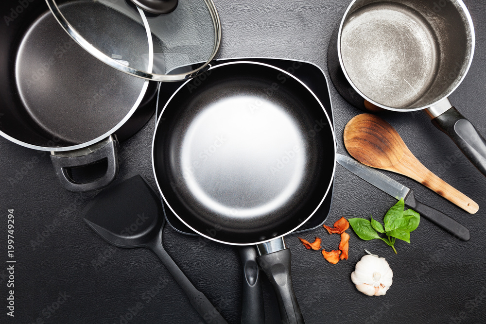黑色皮革桌子上的煎锅和锅的俯视图，用于烹饪背景和食物设计背面