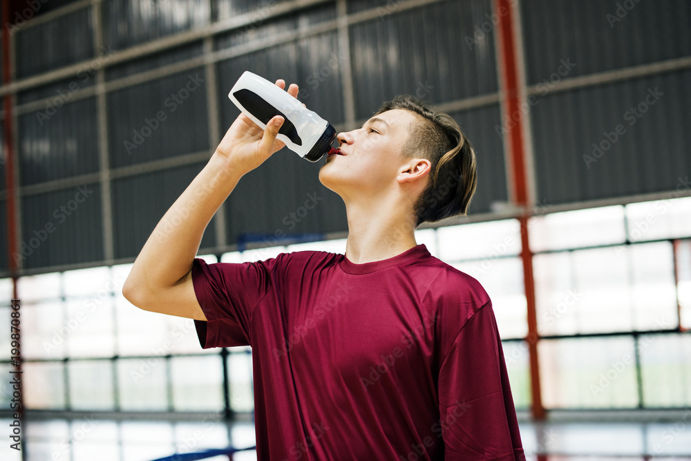 年轻运动型男子饮用运动饮料或水