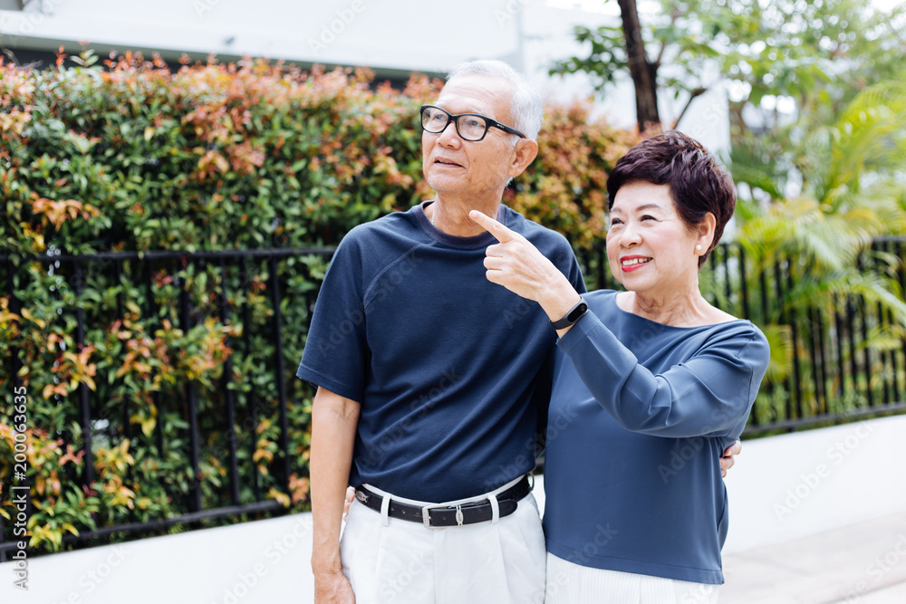 幸福的亚洲老年夫妇在户外公园和房子里散步和指指点点