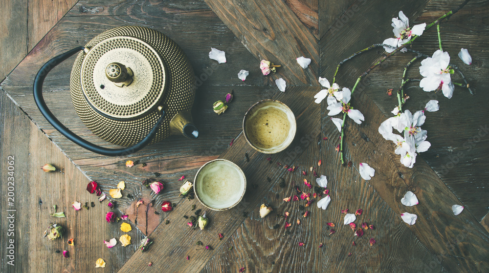 传统亚洲茶道布置。铁茶壶、茶杯、干玫瑰花蕾和花朵的平铺