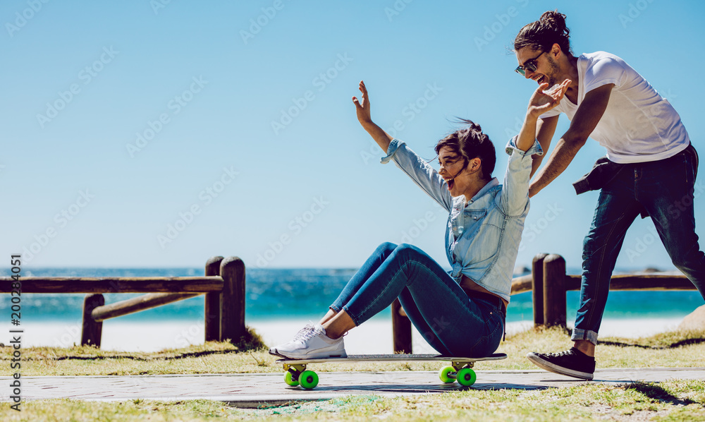 在海滩附近玩滑板的情侣