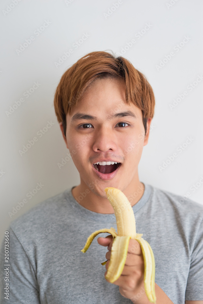 健康的亚洲年轻人在家吃香蕉。
