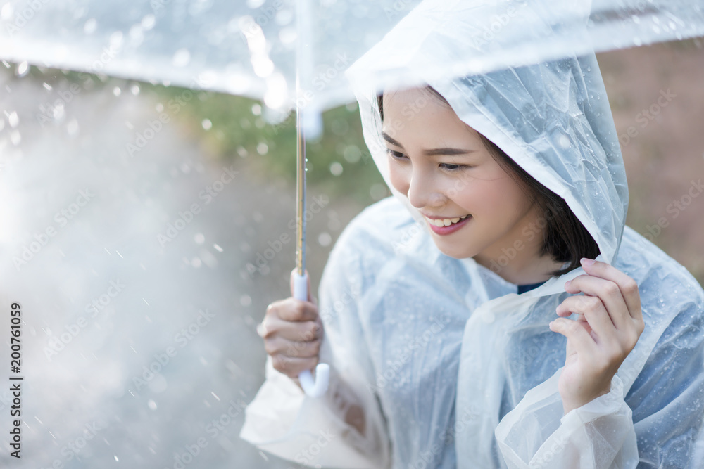 雨天，亚洲女人在户外穿着雨衣。她很开心。