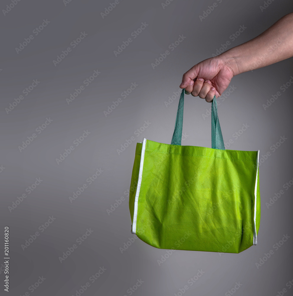 手拿绿色回收环保袋，环保购物或健康有机购物理念
