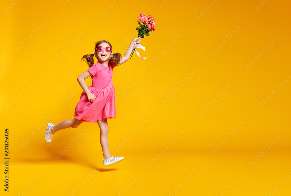 有趣的小女孩在彩色背景上拿着一束鲜花奔跑跳跃。