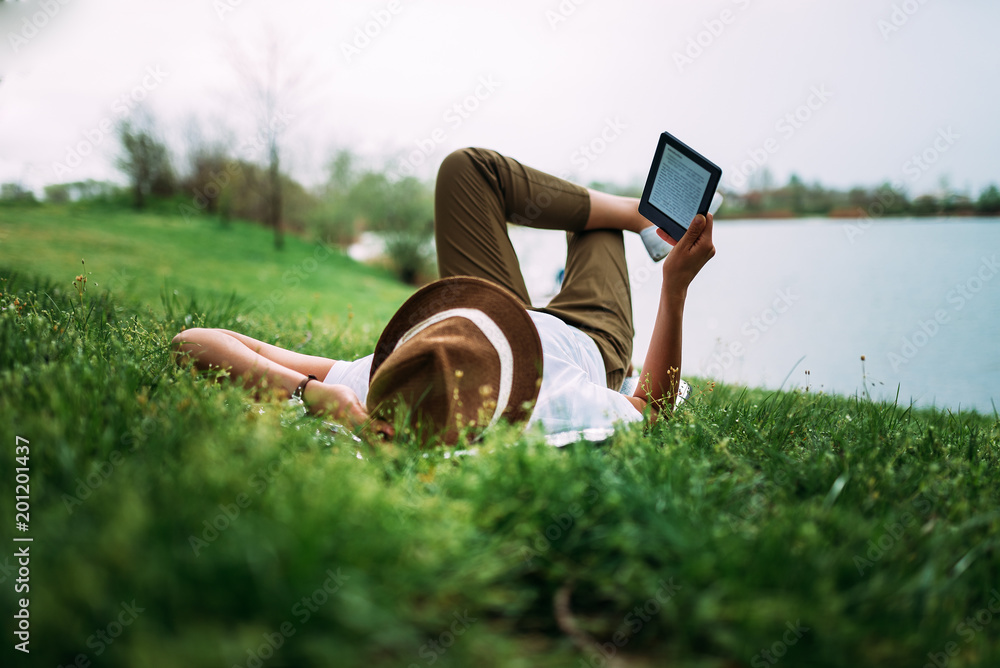 享受户外的一天。躺在草地上，在湖边看书。