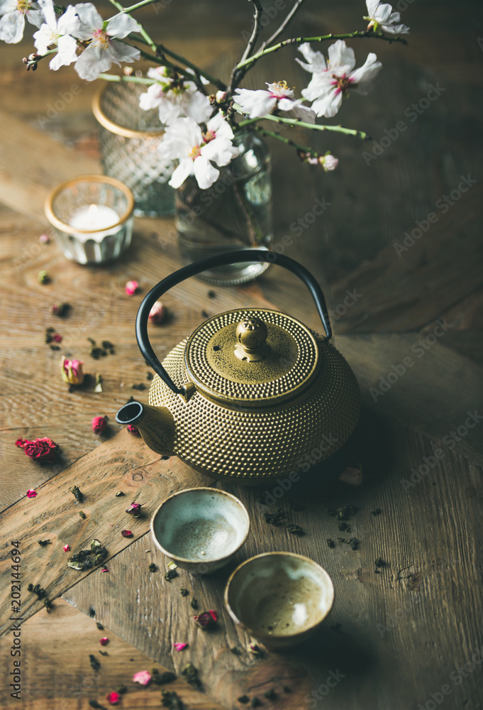 Traditional Asian tea ceremony arrangement. Golden iron teapot, cups, dried rose, candles and almond
