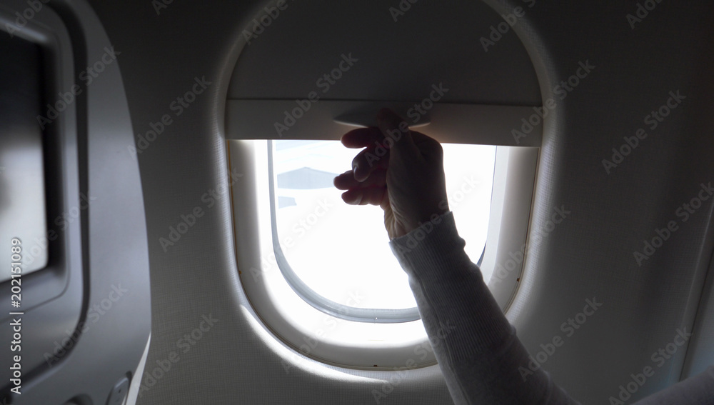 特写：不知名的人拉起飞机窗帘，露出蓝天。