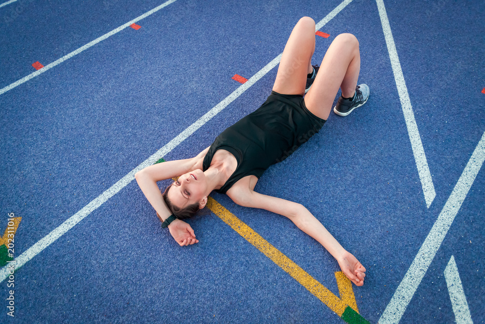 运动型女子训练后躺在跑道上休息的俯视图