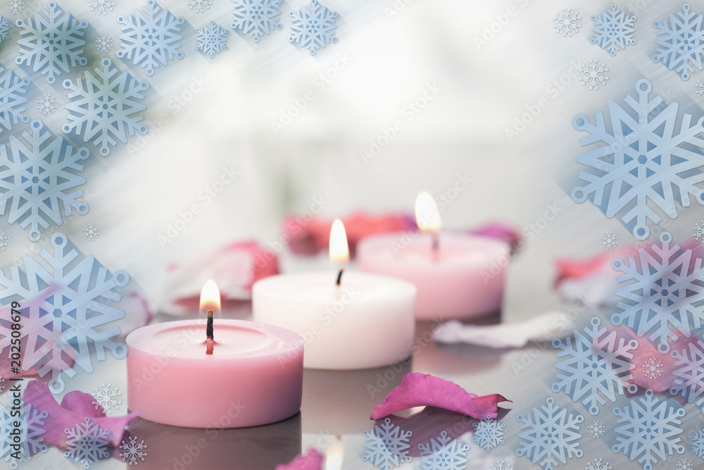 点亮的蜡烛和花瓣在雪花框架上的合成图像