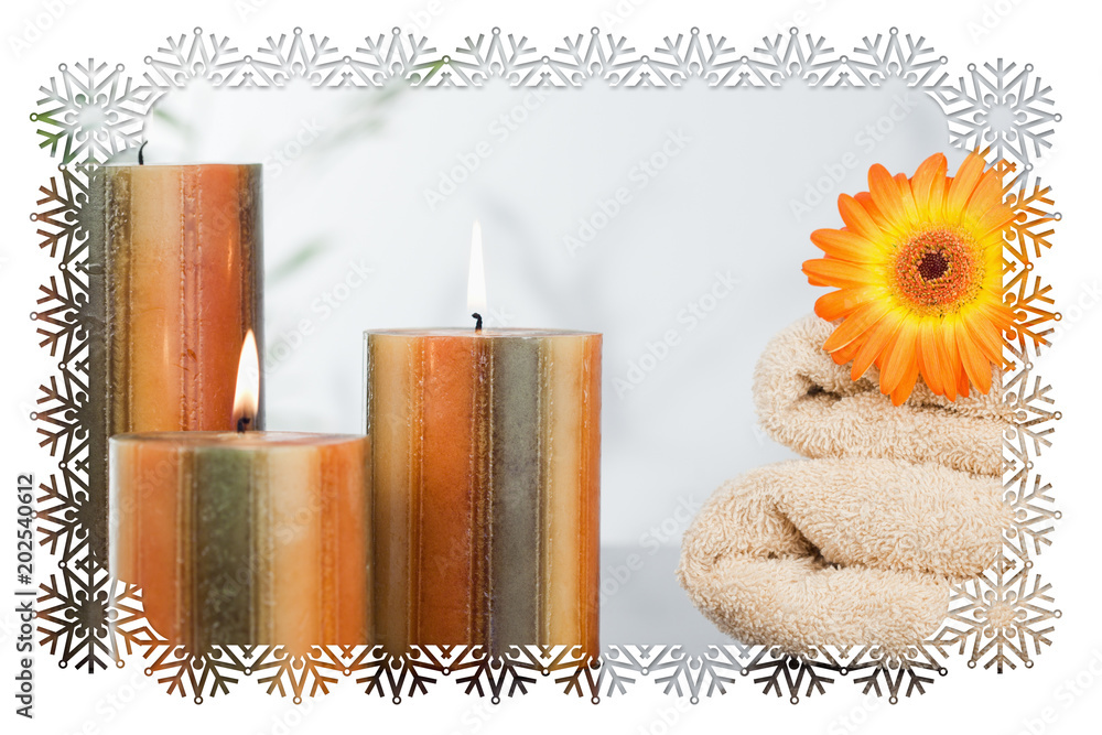 雪花框架与点燃的蜡烛和毛巾上的橙色非洲菊的合成图像