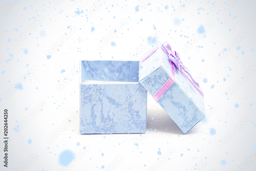 雪花飘落在蓝色礼盒上，紫色缎带靠在另一个礼盒上