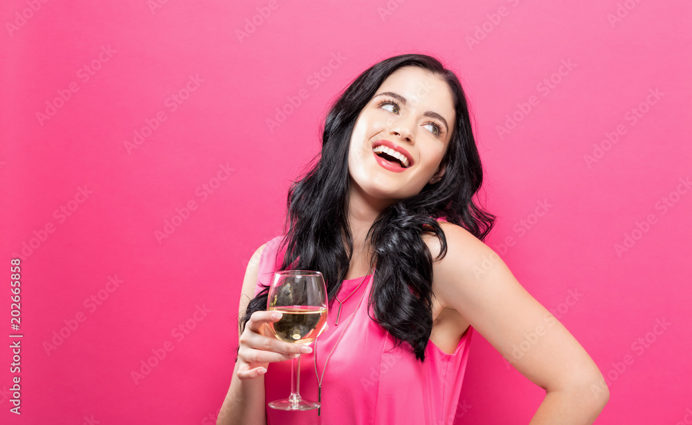 年轻女子在纯粉色背景下饮酒