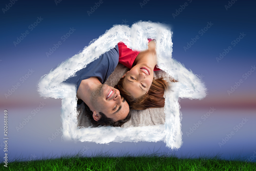 Two friends looking into the sky while lying on a quilt against green grass under blue and purple sk