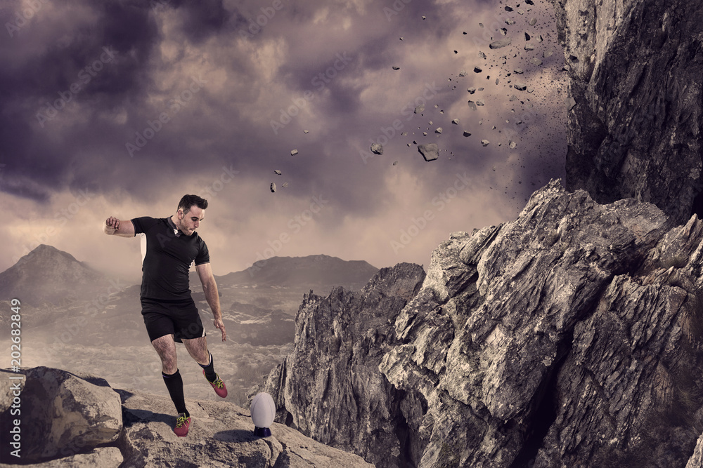 Rugby player kicking the ball against rock crashing down from cliff