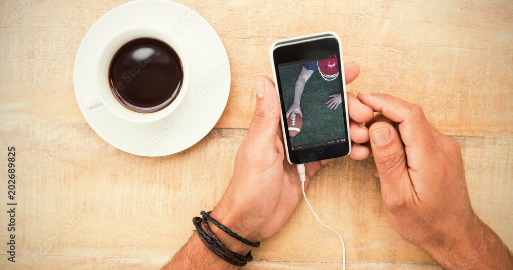 美国足球运动员在一杯咖啡旁手持智能手机触地得分