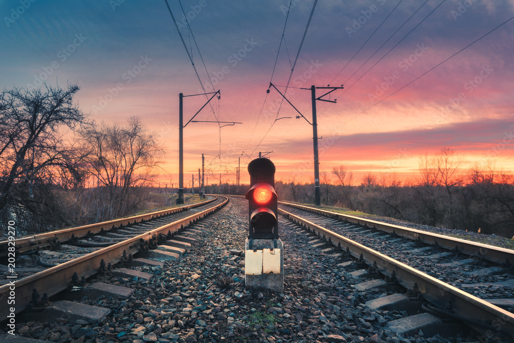 日落时，阳光明媚的天空下，挂着信号灯的火车站。五颜六色的工业景观