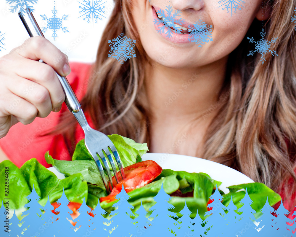 一位兴高采烈的女士在蓝色的雪花和冷杉树上吃沙拉的特写