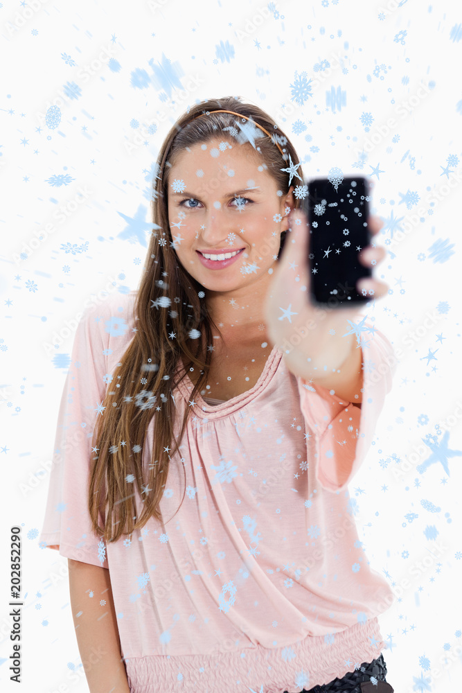 一位微笑的女士在下雪时展示智能手机的特写合成图
