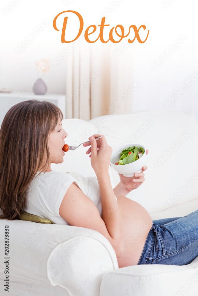 排毒这个词反对美丽的孕妇躺在沙发上吃沙拉