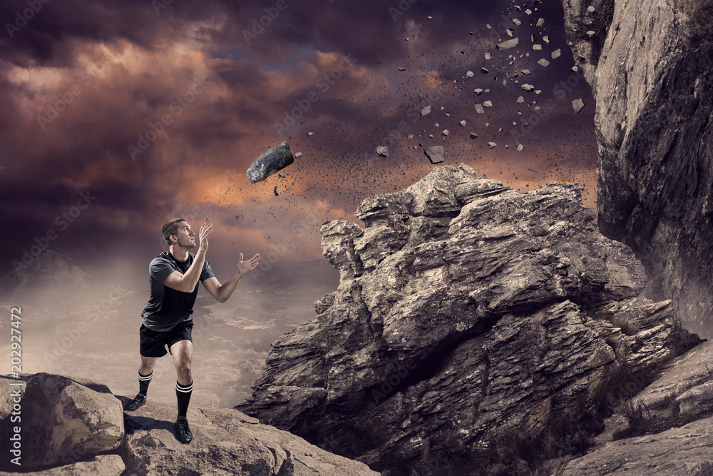 橄榄球运动员在悬崖上的岩石上接球