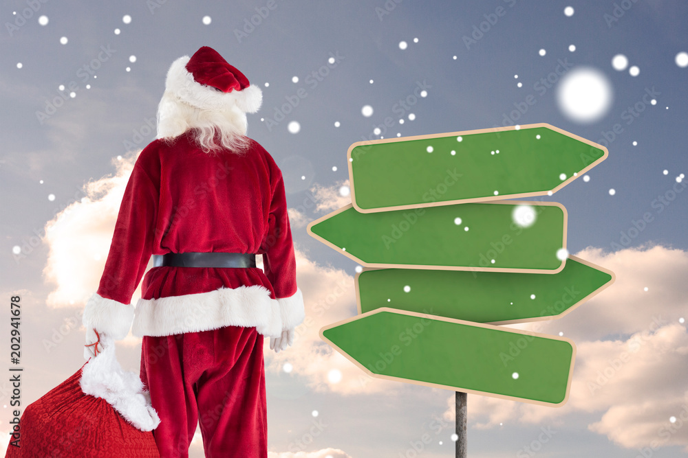 圣诞老人背着一袋礼物对着空的绿色路标