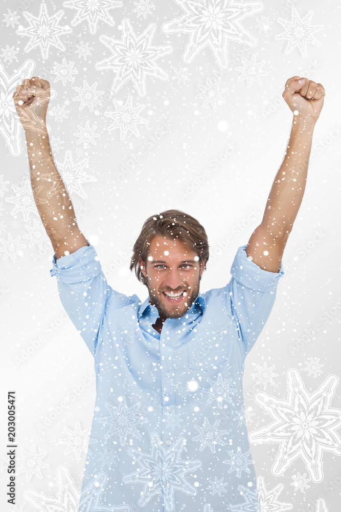 快乐的男人举起双臂，对着银色的雪花庆祝成功