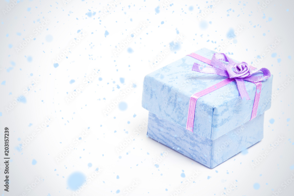 雪花飘落在紫色缎带的蓝色礼盒上