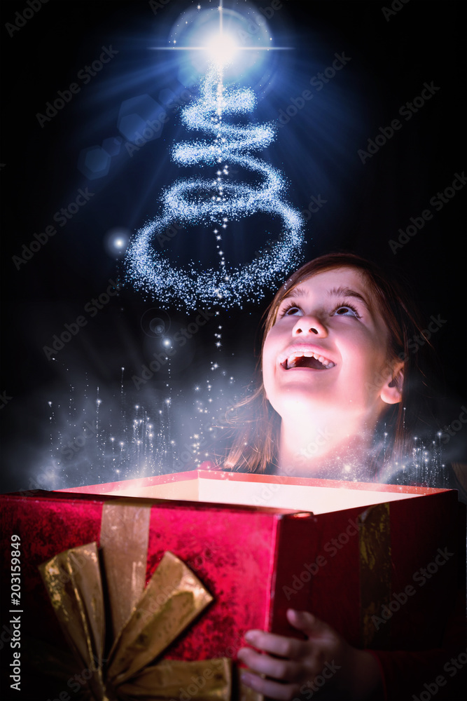 小女孩在圣诞树设计的背景下打开一份神奇的圣诞礼物