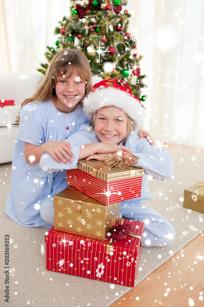 Composite image of Happy brother and sister holding Christmas presents with snow falling