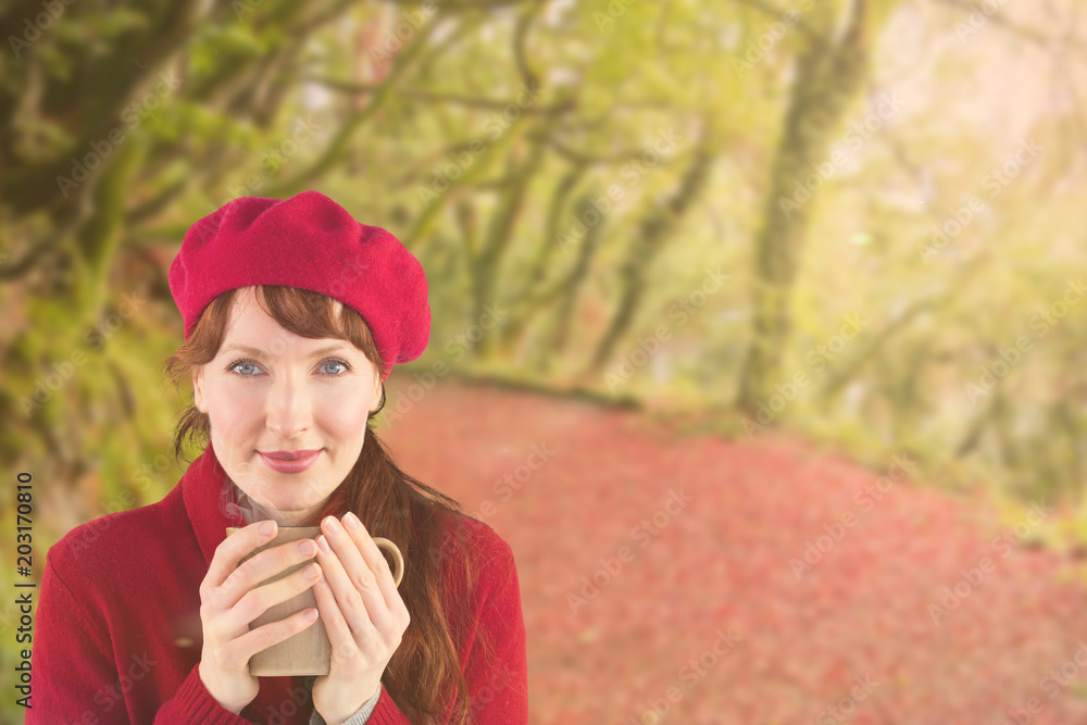 一个女人拿着一个温暖的杯子对抗森林中平静的秋景