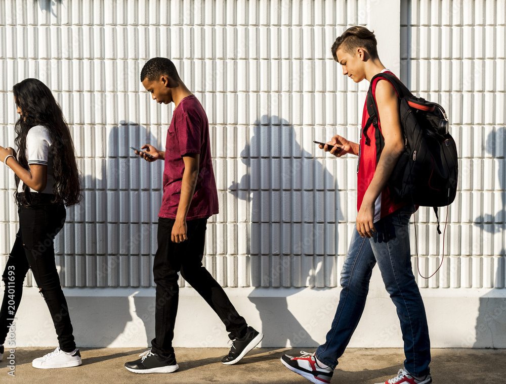 一群年轻的青少年朋友放学回家时使用智能手机成瘾概念
